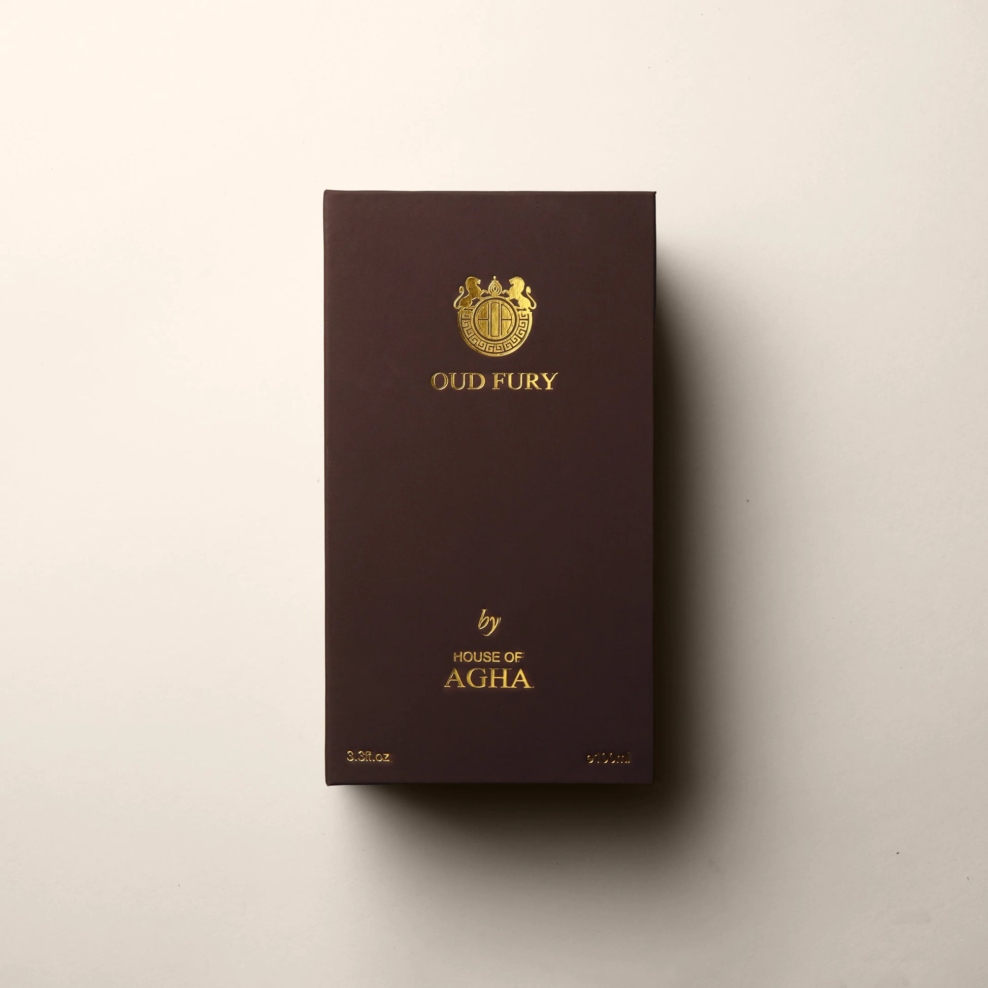 A wooden-textured box for Tobacco Enigma Eau de Parfum by House of Agha, displaying the brand logo and name in gold, with a capacity of 3.3 fl oz (100ml), set against a plain background.
