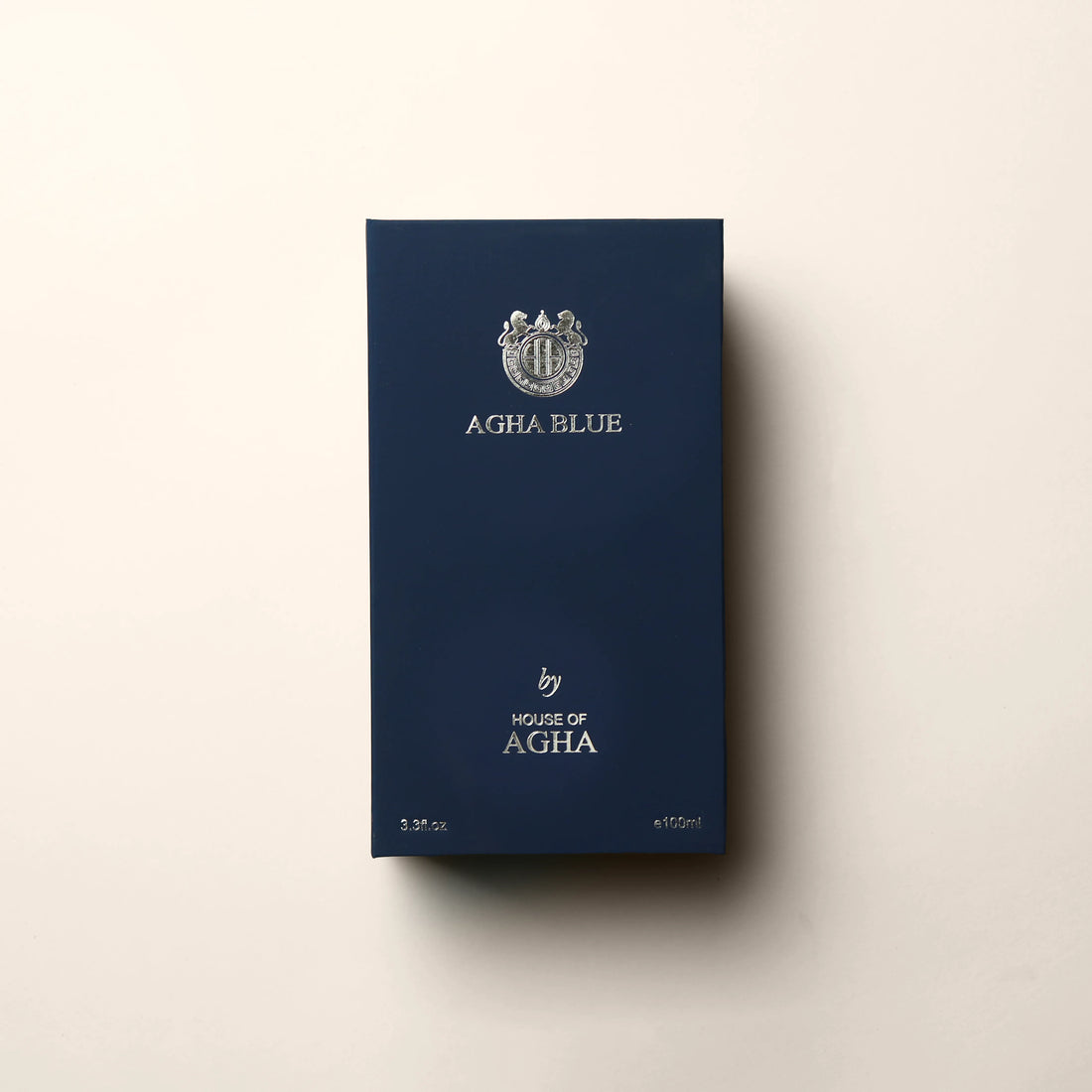 A bottle of Agha Blue Eau de Parfum by House of Agha, featuring a deep blue glass bottle with a white cap and elegant silver branding, placed against a plain background.